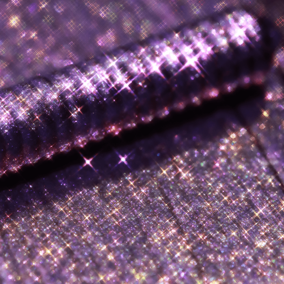 Close-up of a mascara topper with pink opaline color, purple glitter, and star-shaped holographic shimmer.