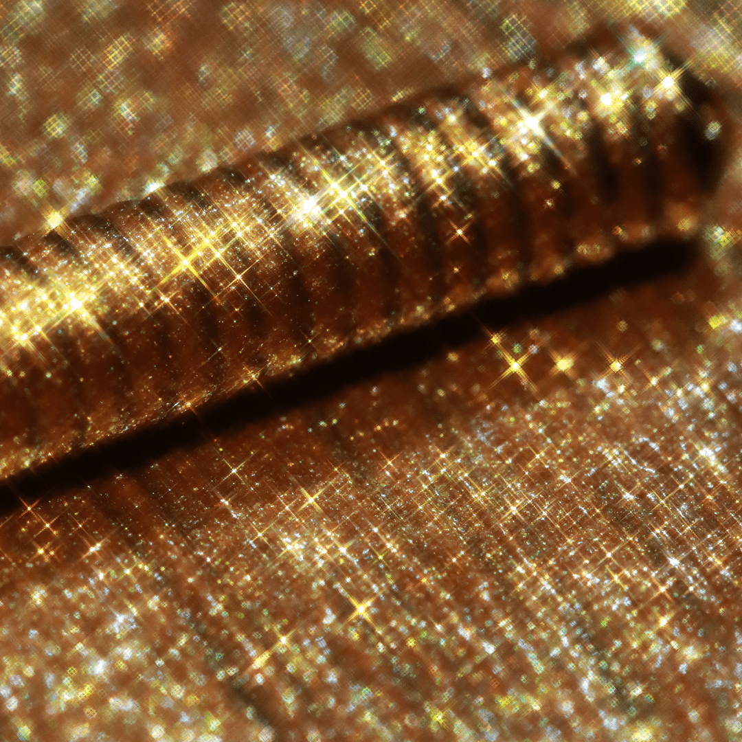 A close-up of an applicator with gold shimmer is shown, highlighting its metallic finish.
