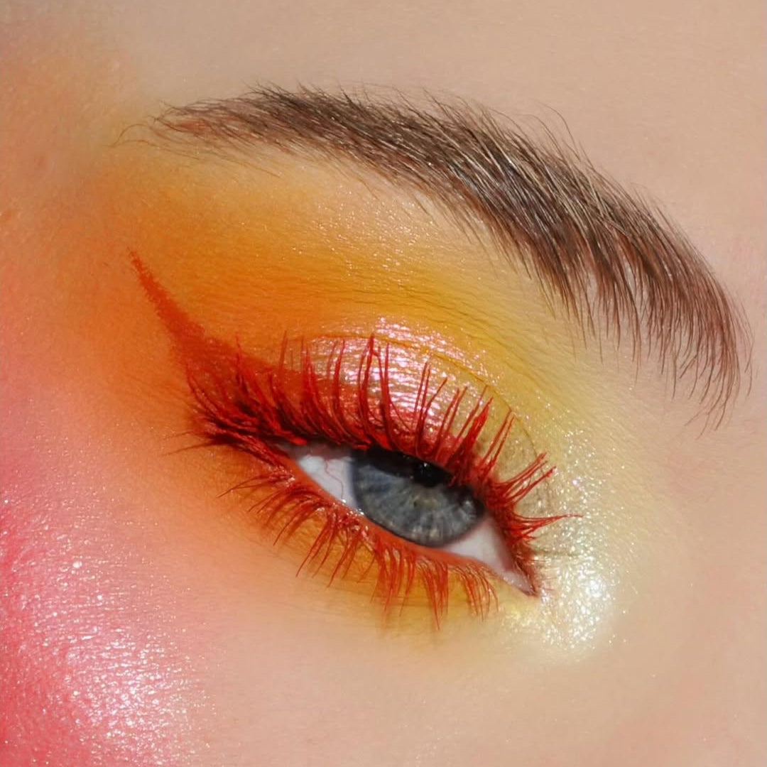 Close-up of an eye with Ruby Crown mascara, and orange-yellow eyeshadow