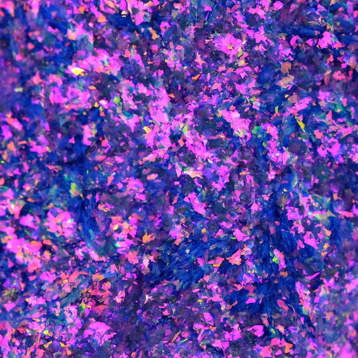 Close-up of iridescent flakes in purple, pink, blue, and yellow creating a textured shimmer pattern.