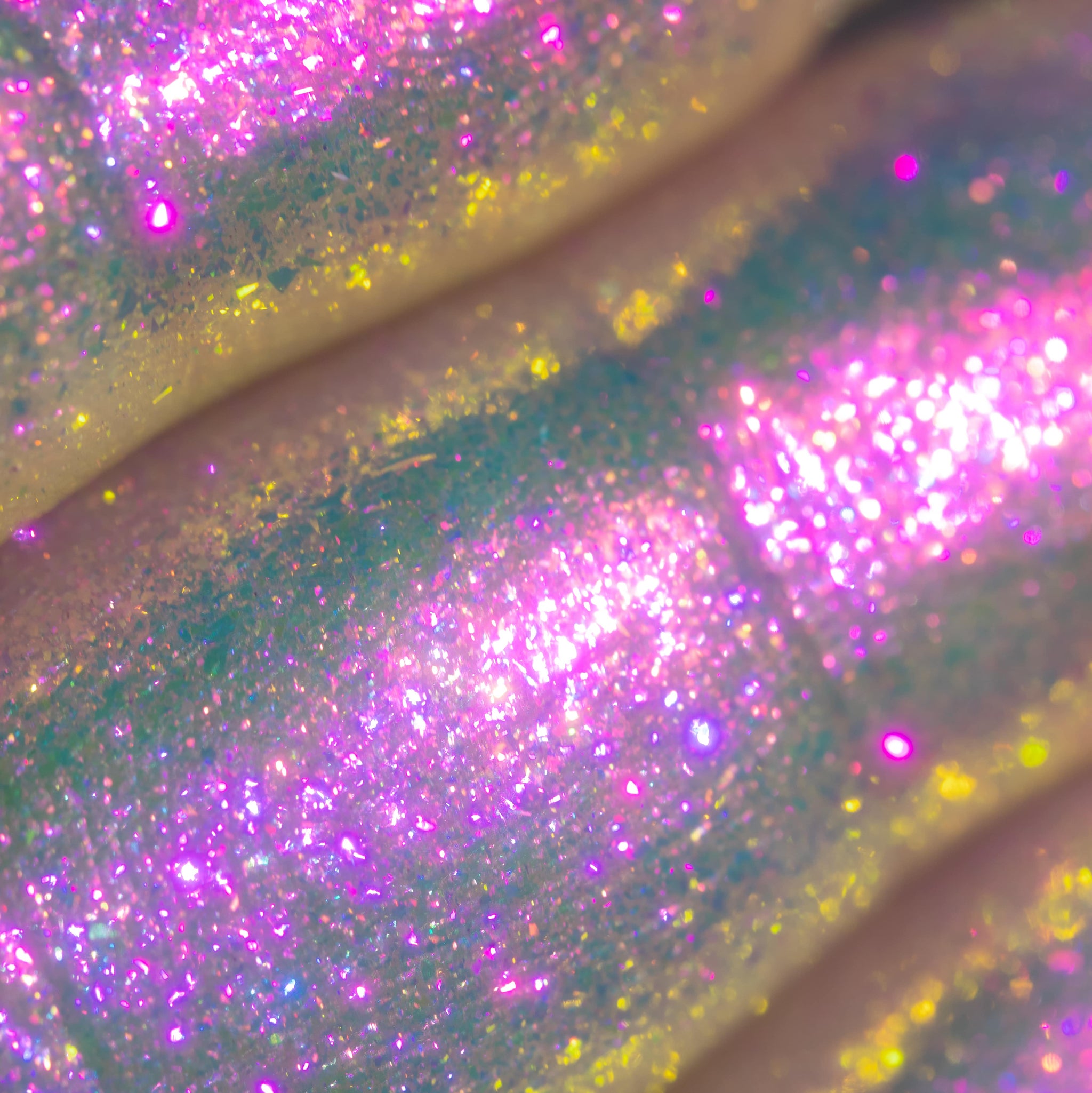 Close-up of iridescent pink, yellow, and purple glitter on a textured, curved holographic surface.