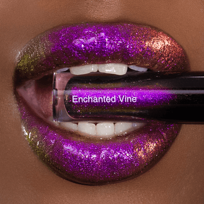 Lips with a glossy purple, pink, and gold shimmer finish are shown holding a lip gloss tube with logo Enchanted Vine.