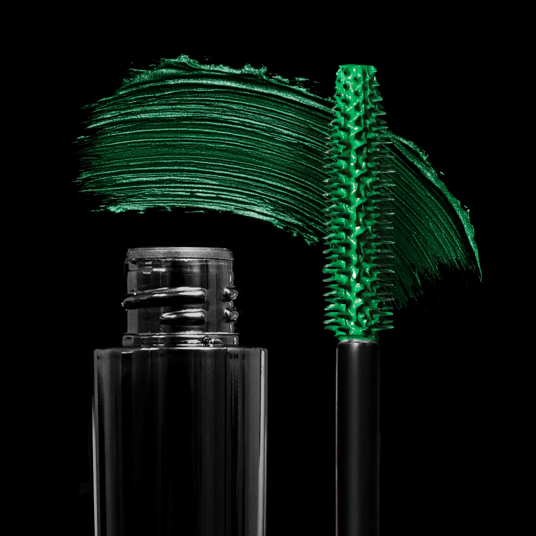 A green mascara brush and a bold green mascara swipe are shown on a plain black background.