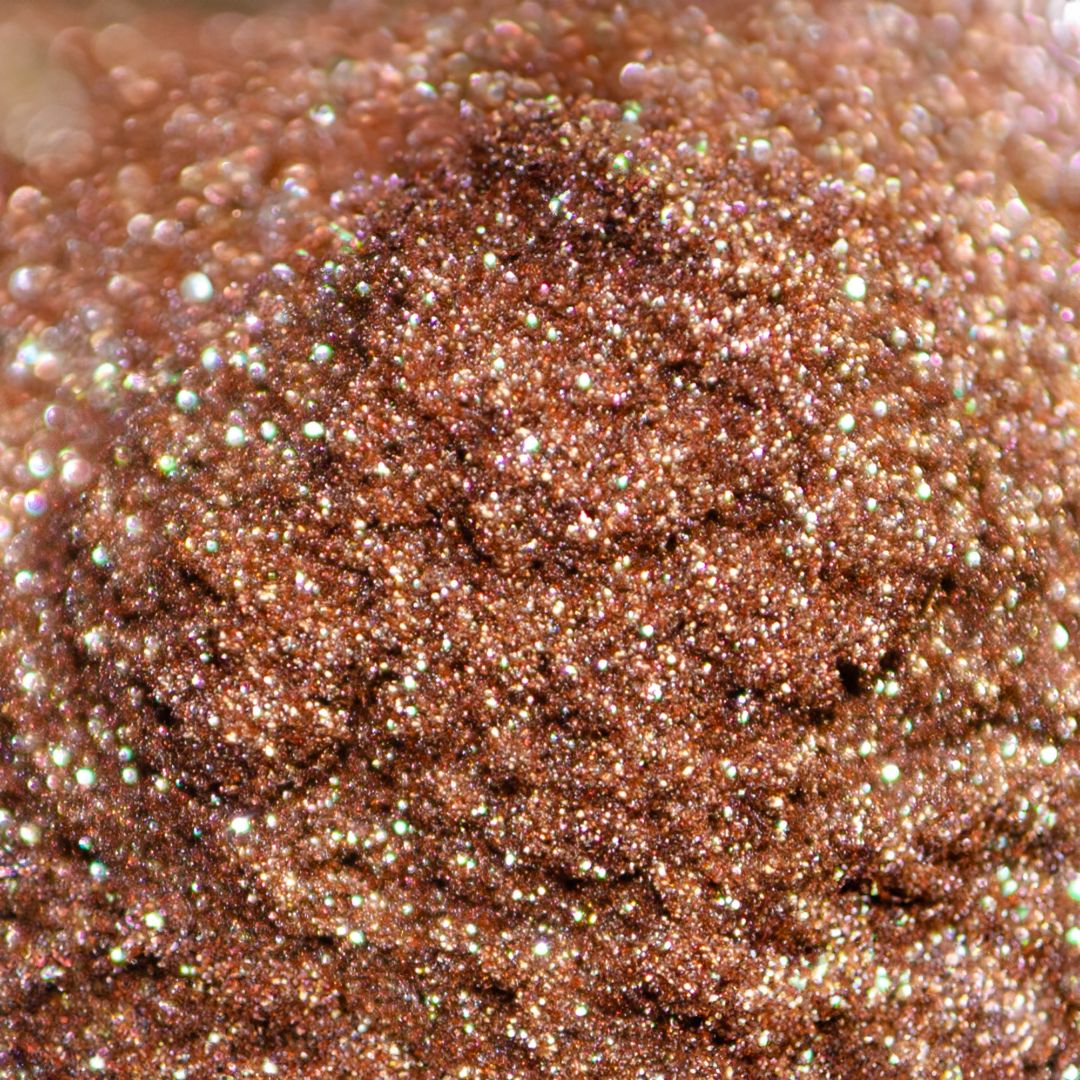 A container of coppery glitter with a shimmering, textured appearance.