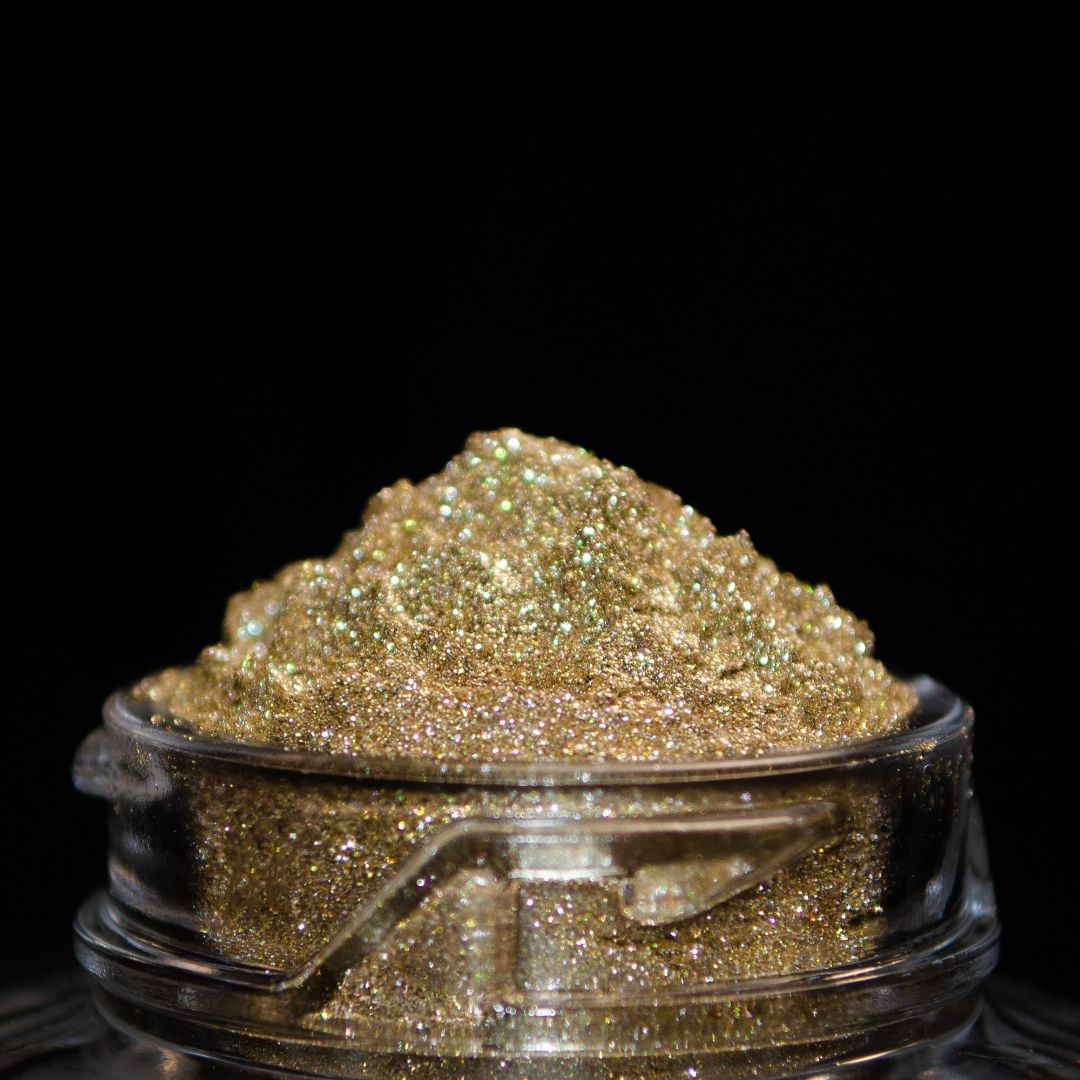 A clear jar filled with gold glitter powder sits against a black background.