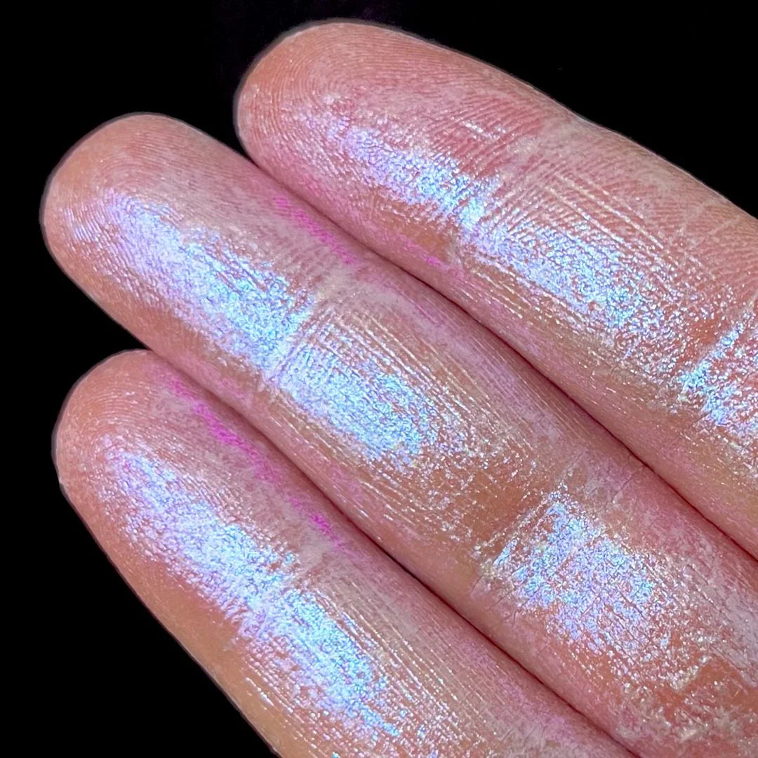 Fingers coated with shimmery pink powder are shown against a plain black background.