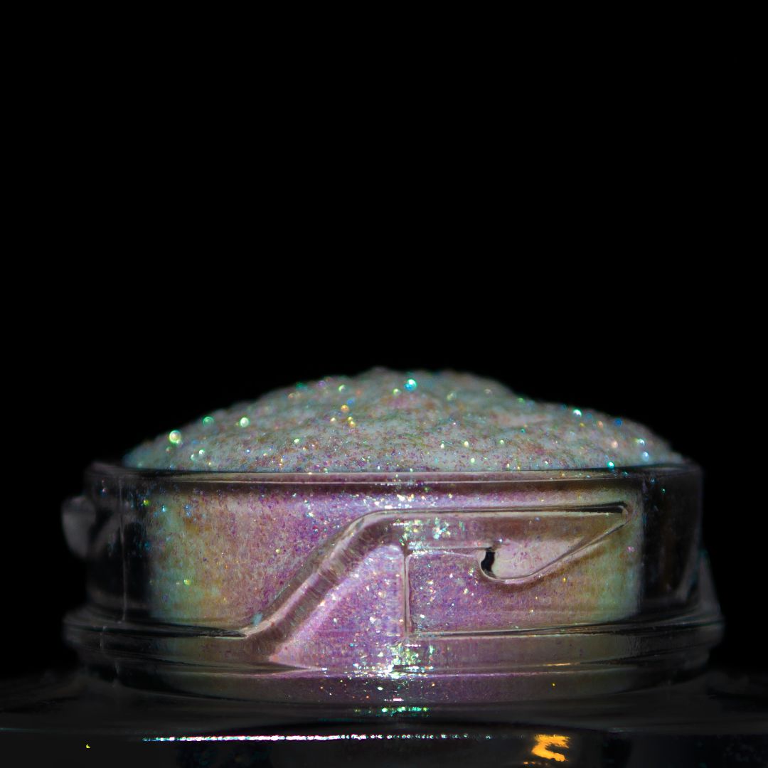 A small clear jar holding iridescent glitter against a black background.