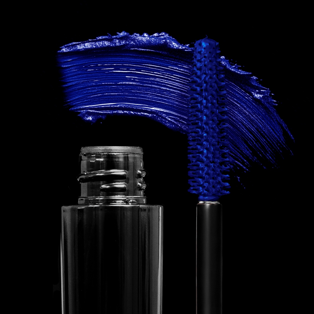 An open mascara tube with a blue brush and a bold blue swipe is shown against a black background.