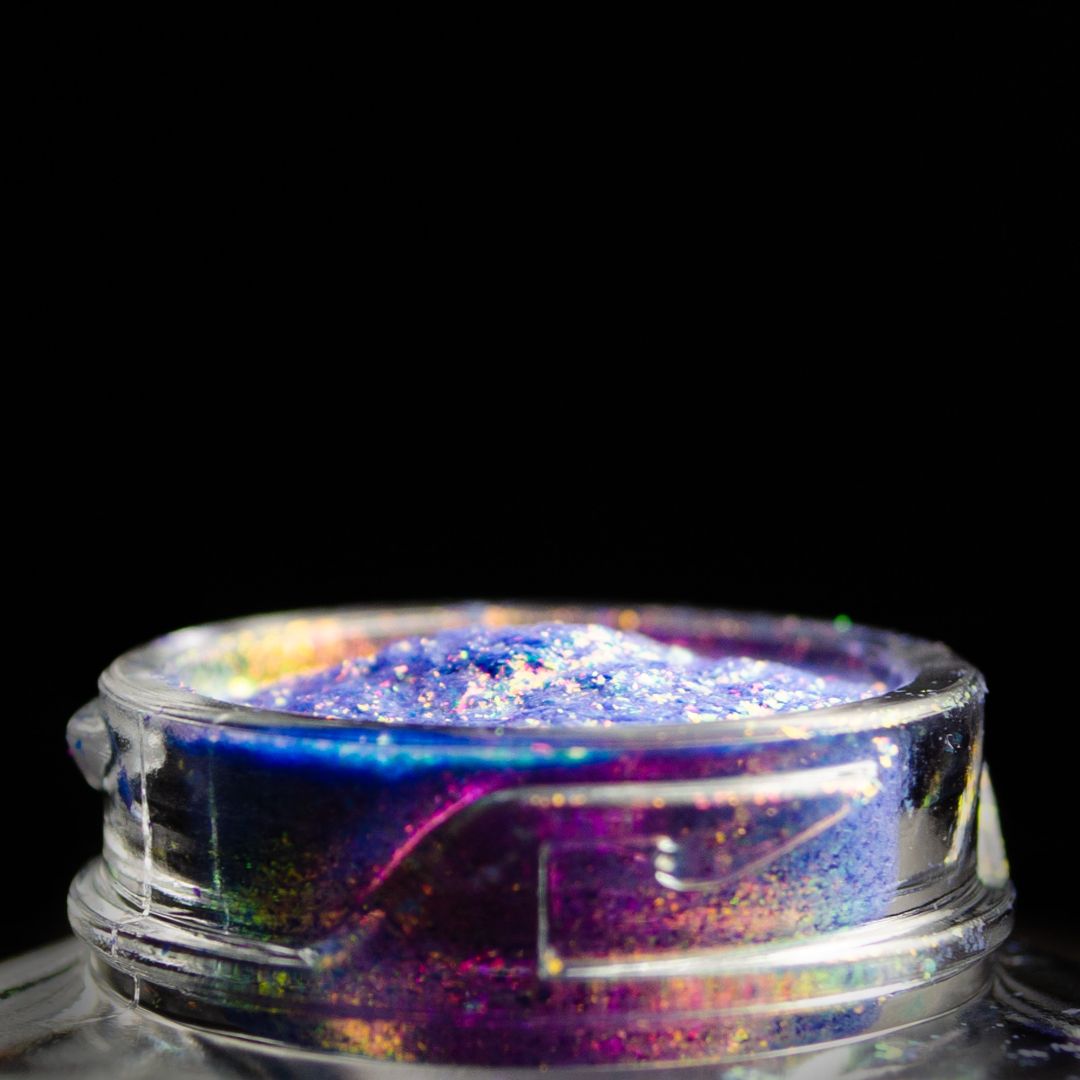 A clear jar filled with iridescent purple and blue glitter sits against a black background.