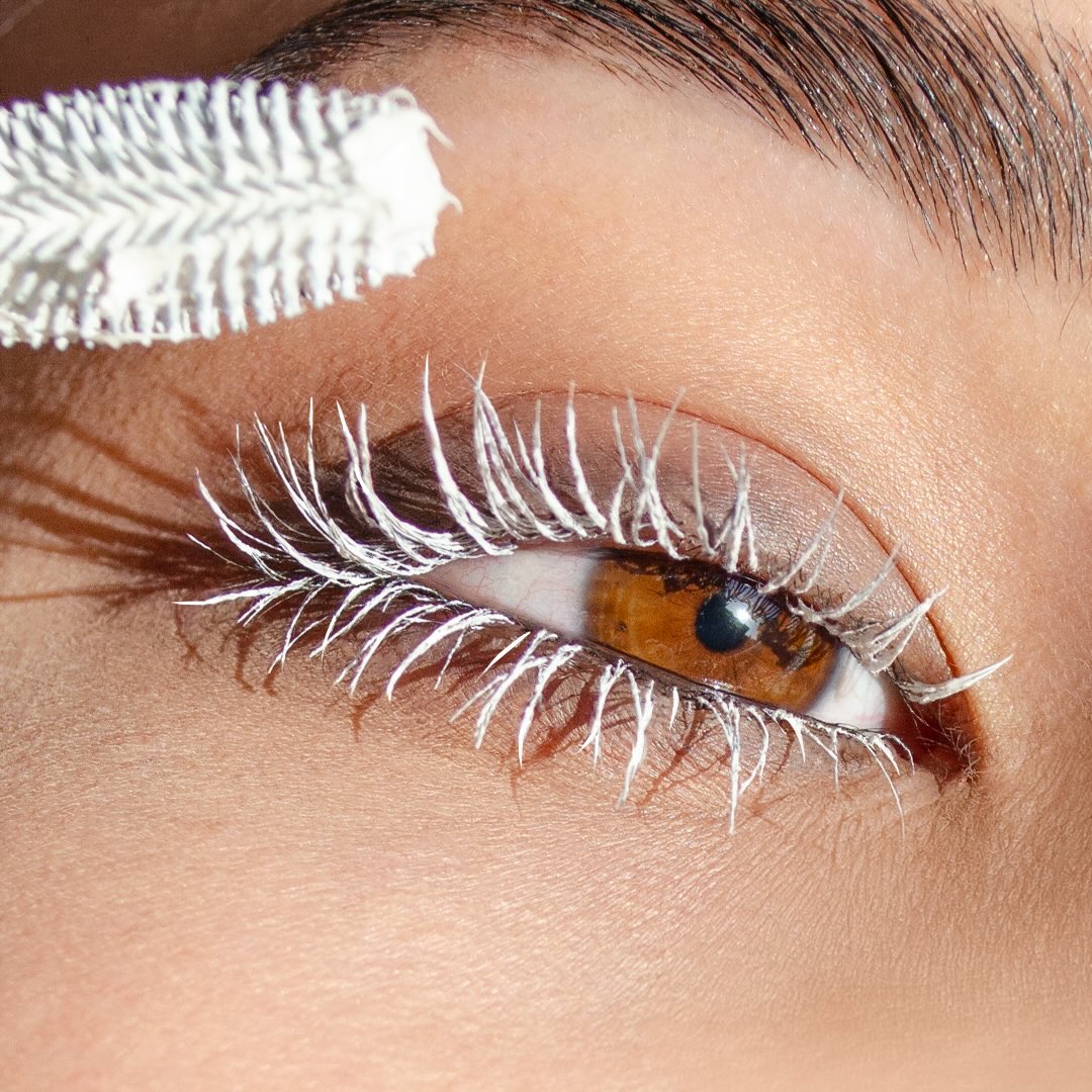 Close-up of a brown eye with white mascara visible on the upper lashes.