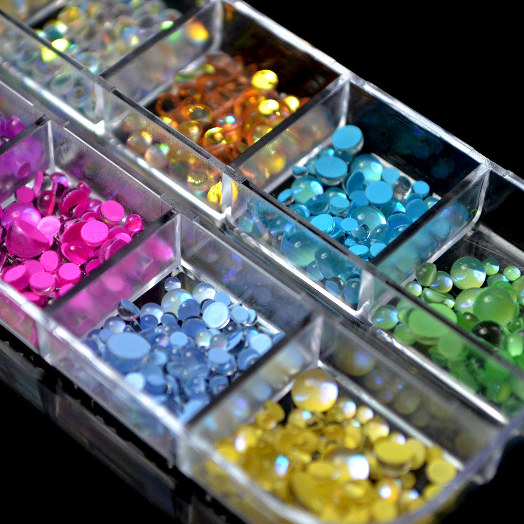 A box with round rhinestones in pink, orange, blue, green and yellow organized in separate compartments.