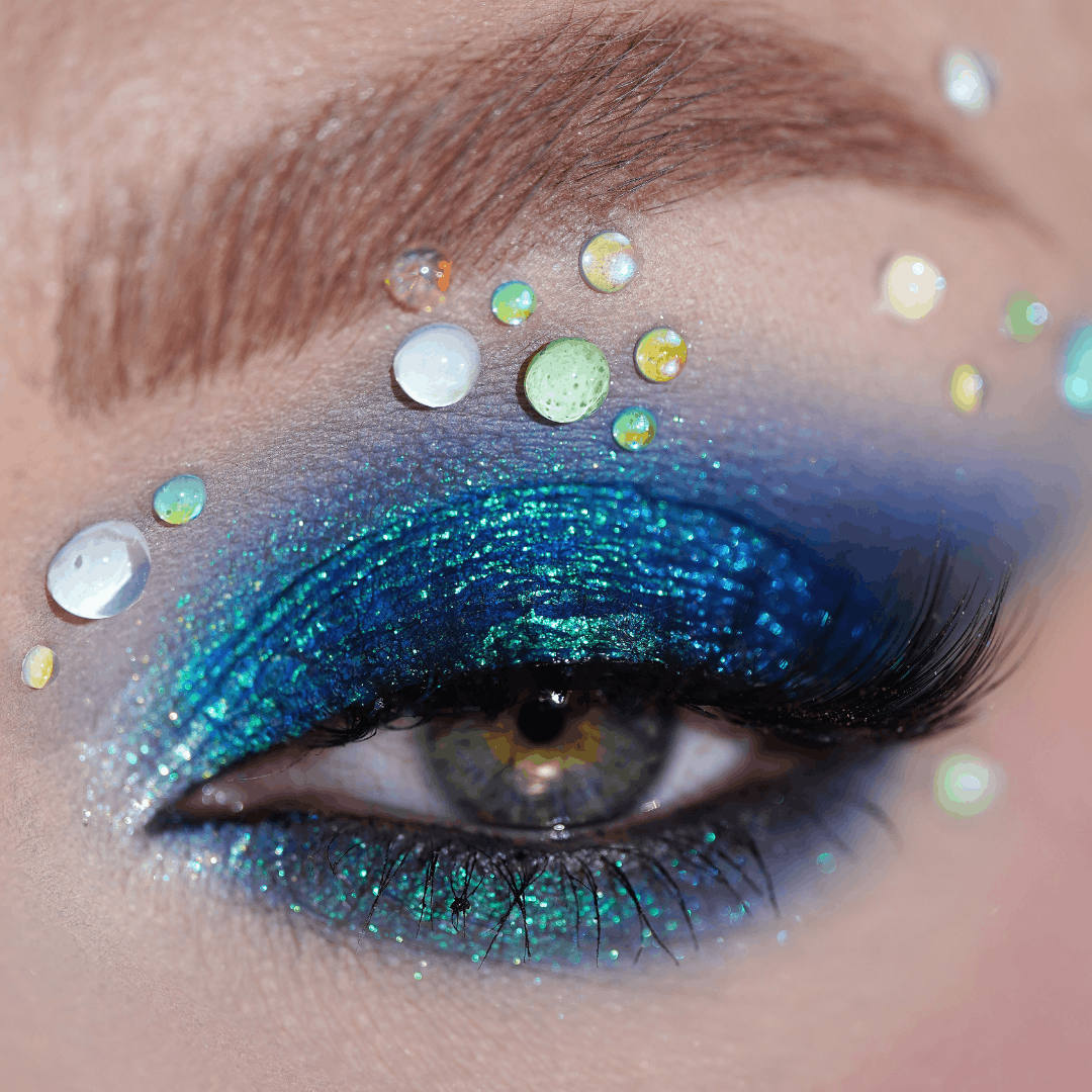 Close-up of an eye with dark blue eyeshadow and droplet gems