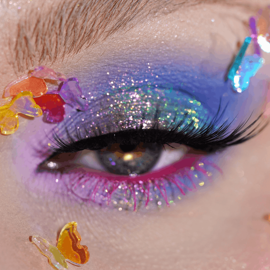 Close-up of eye with blue and purple eyeshadow with butterfly gems around it